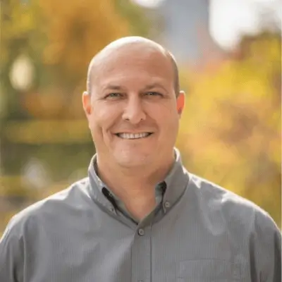 Smiling bald man in a gray shirt outdoors